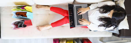 Woman is sitting on couch at home and is shopping online.の写真素材