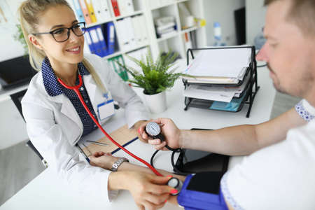 Doctor cardiologist measuring patient blood pressure in clinicの写真素材