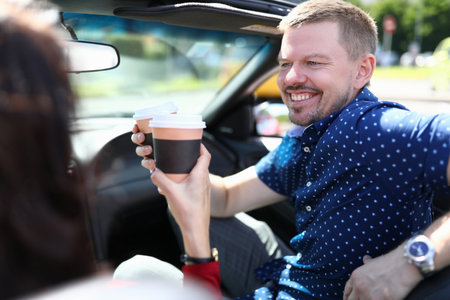 Man and woman are driving in car and drinking coffeeの写真素材