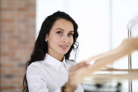 Young woman standing near rack with hangersの写真素材