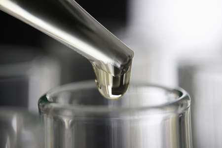 Yellow liquid dripping from pipette into test tube closeupの写真素材