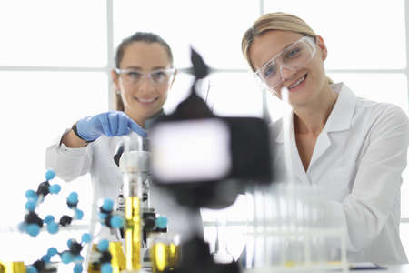 Women scientists conducting chemical experiment and shooting with cameraの写真素材