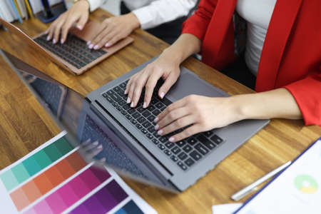 Women designers typing on laptop keyboard in office closeupの写真素材