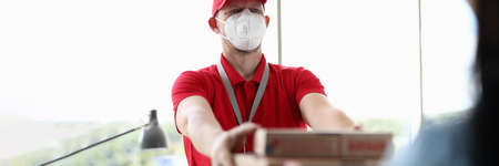 Courier wearing protective mask delivers pizza closeupの写真素材