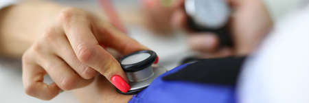 Female doctor measures pressure of a patient with medical office.の写真素材