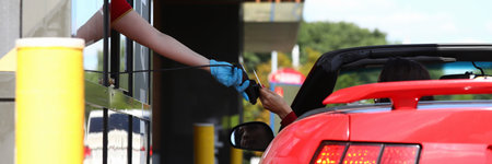 Woman in convertible pays with bank card at payment point.の写真素材