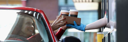Woman in convertible car picks up tea and coffee in Mcdriveの写真素材