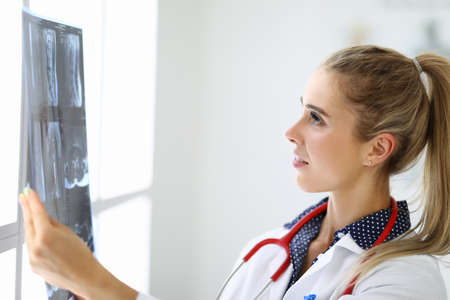 Female doctor looks at an x-ray in medical office.の写真素材