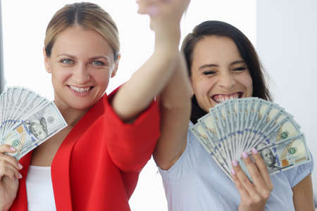 Two smiling businesswoman are holding American bills.の写真素材