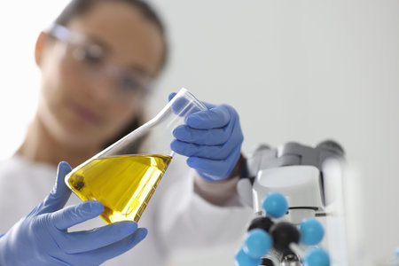 Researcher holds flask with yellow liquid closeupの写真素材