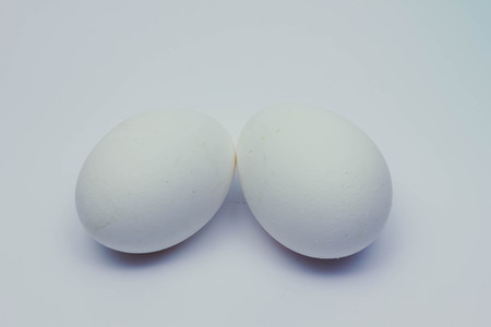 Close-up view of raw chicken eggs in egg box on white wooden backgroundの写真素材