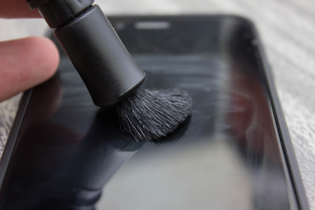 Close up of a woman cleaning mobile smart phone with fabric in dark background, blank text, , selective focus on finger fabricの写真素材