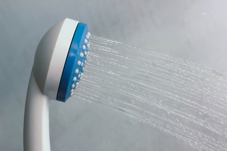 Open shower mixer in bathroom, tinted black and white image, horizon format