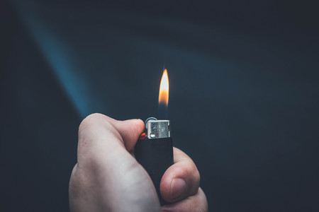 Hand igniting fire lighters on a black backgroundの写真素材