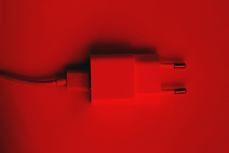 White smartphone charger isloated on red background, european type.の写真素材