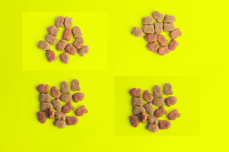 Dry pet food in bowl on yellow background top view macroの写真素材