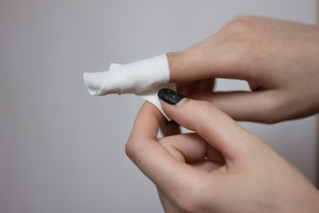 Injured painful finger with white gauze bandageの写真素材