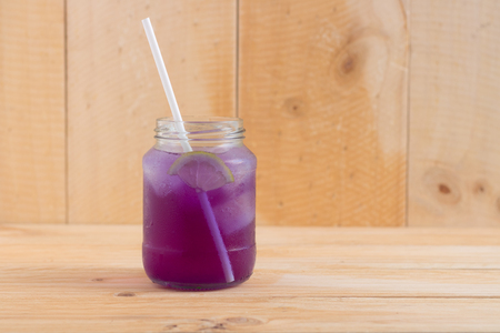 Purple butterfly pea juice decorated with lemon on wooden tableの写真素材