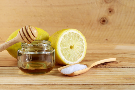 Jars of honey and lemons and salt on wooden tableの写真素材