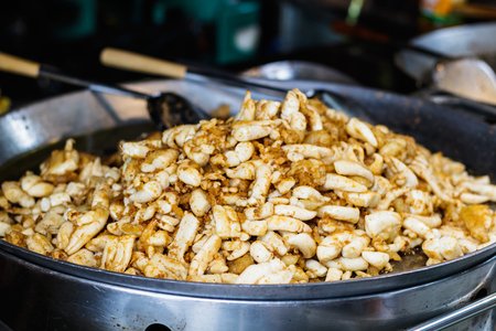 fried squid eggs cooking in a large pan with ladle. steet food. thai style food.の写真素材