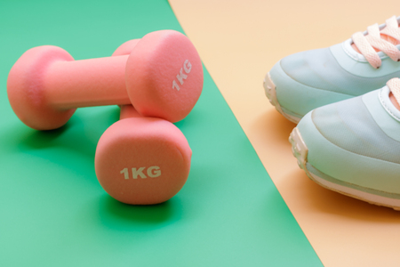 sport, healthy lifestyle and objects concept - close up sport shoes and dumbbells on green and orange background. Concept healthy lifestyle, sport and diet. Sport equipment. Copy space.の写真素材