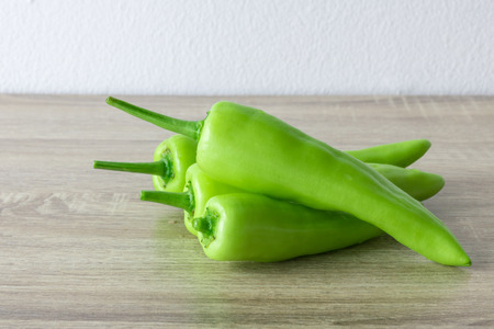 Green vegetables. Organic long green peppers on wooden table background.の写真素材