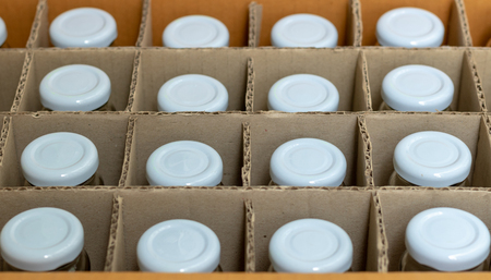 Glass bottles with white bottle caps in a cardboard box, Top view, Packaging concept.の写真素材