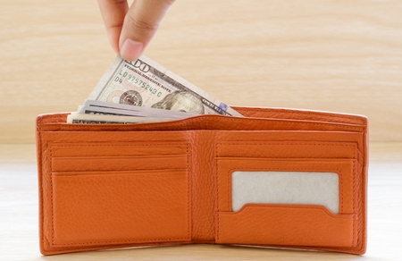 Hand stealing out money from wallet on wooden table.の写真素材