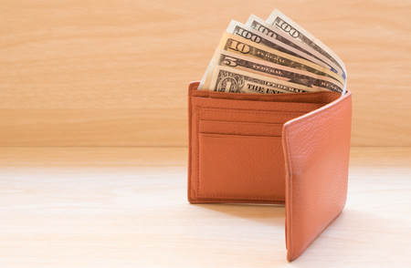 dollar banknotes and wallet on wooden table