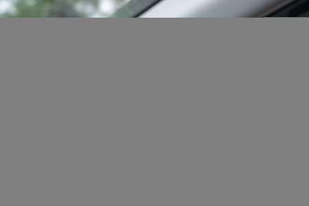 A young woman's hand is holding the black steering wheel of a car while driving.の写真素材