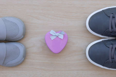 Big and small sneaker shoes on wooden background. Father's day celebration. Top-view composition.の写真素材