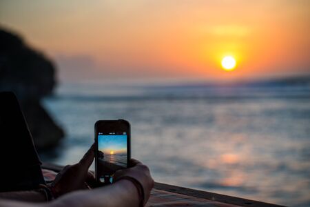 Person takes picture of sunset with their smartphoneの写真素材