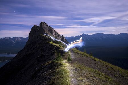Light trail running along ridge of mountain lit up at nightの写真素材