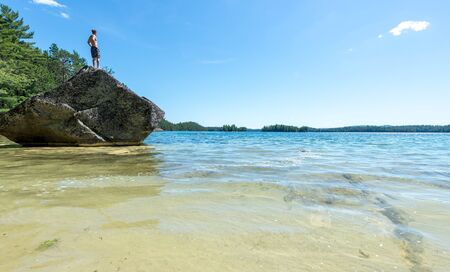Man standing on a rock   beach   warm summer dayの写真素材