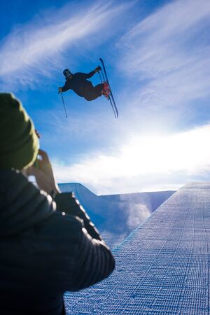 Photographer takes photo of halfpipe skier doing a grab trickの写真素材