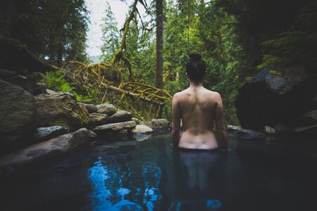 Young caucasian woman standing in natural hot spring bare backの写真素材