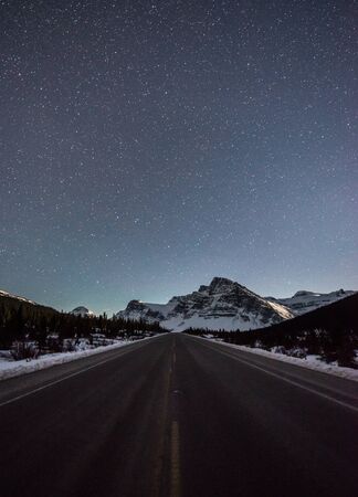 Icefields Parkway Road into the mountains on a clear starry nightの写真素材