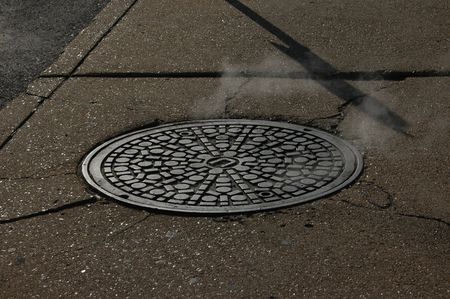                                 Steam rising from a manhole cover in a large US cityの写真素材