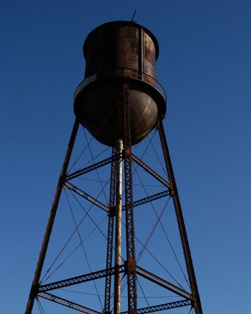 Old rusted water tower against a blue skyの写真素材