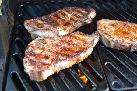 Three steaks on the grill ready for a nights mealの写真素材