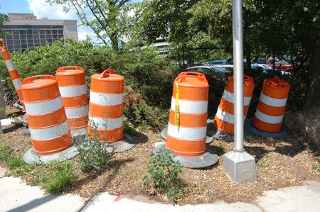 Orange and white traffic barrels ready for use in the cityの写真素材