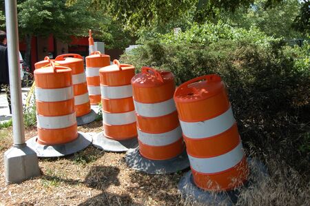 Orange and white traffic barrels ready for use in the cityの写真素材