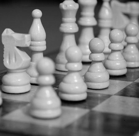 A row of pawns on a chess board ready for play, shown in black and white.