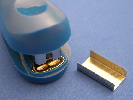 A closeup view of a small stapler on a blue backgroundの写真素材