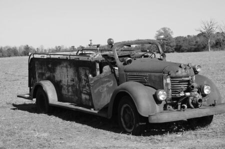 Old rusted firetruck in the field shown in black and white.のeditorial素材