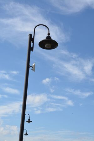 Street light with a curved lighted shown during the day.の写真素材