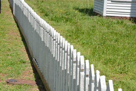 A white picket fence near an old houseの写真素材