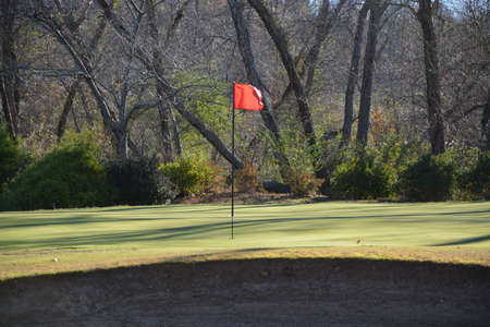 Near the flag on a golf course during the fall of the year. の写真素材