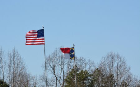 American and North Carolina flags flying in the breeze during the spring of the year.の写真素材