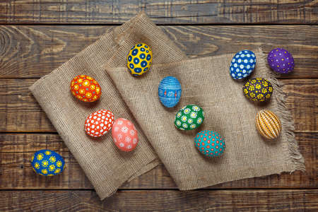 Hand painted colorful easter eggs on on sackcloth a top view and old brown wooden board
